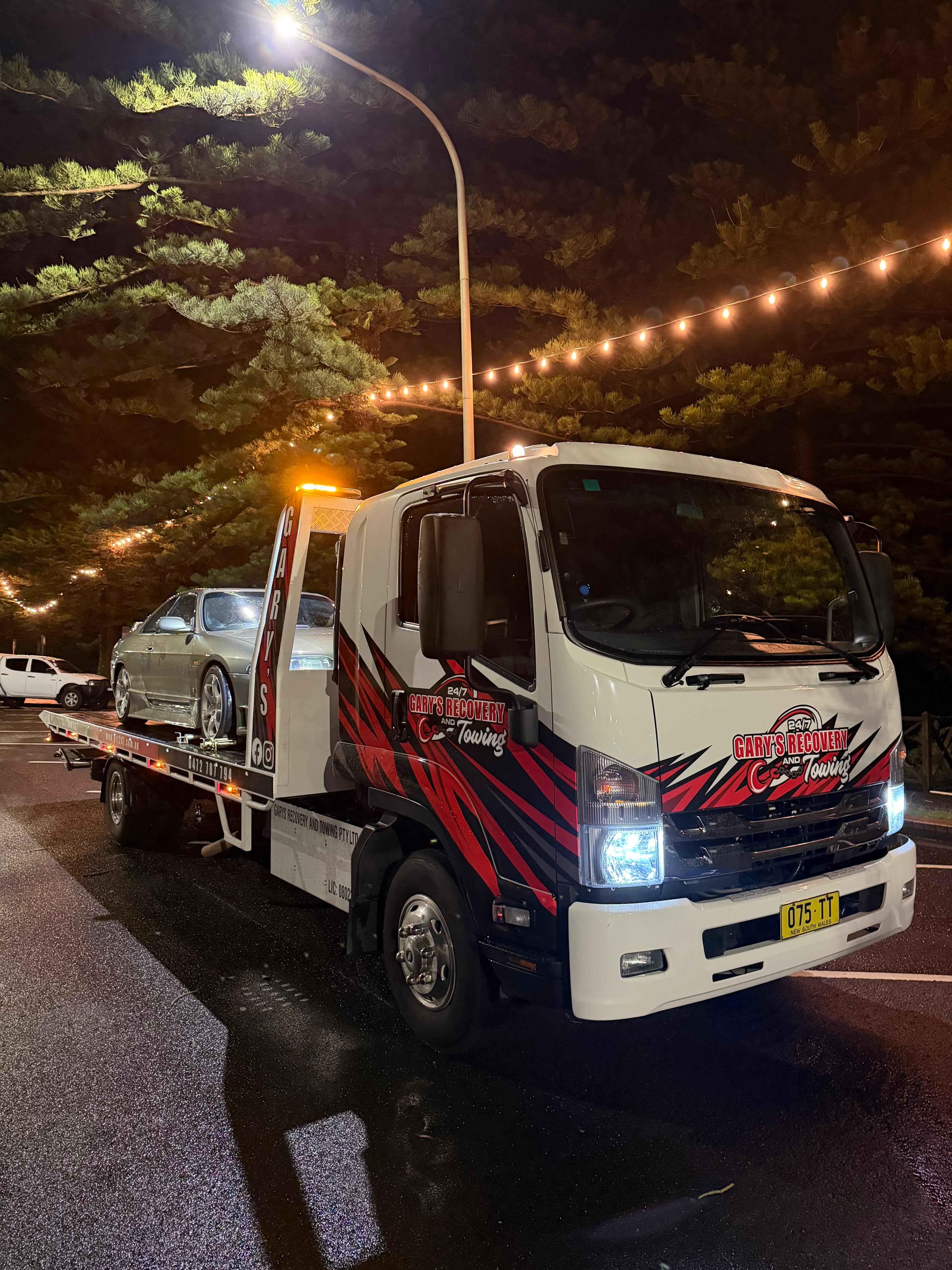 Gary's Recovery & Towing truck at night with sports car